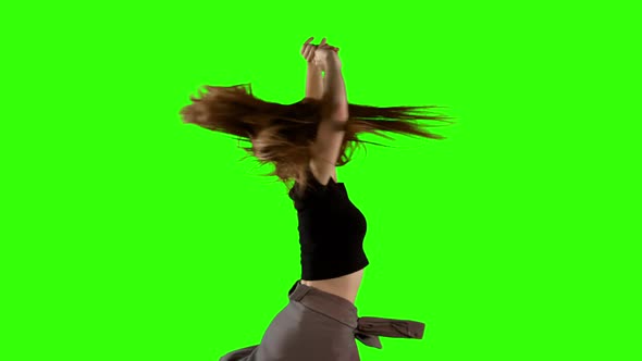Young woman dancing against green screen background