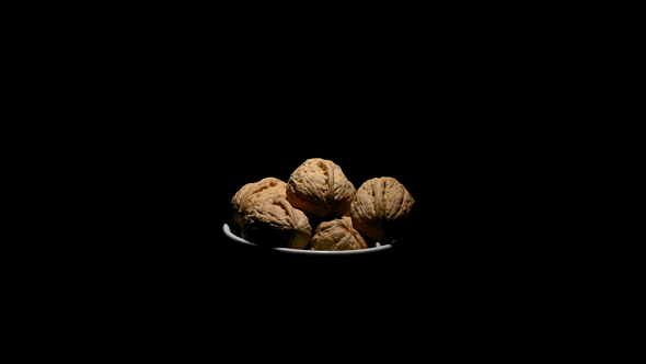 Walnuts Turning in a White Bowl on Black Background