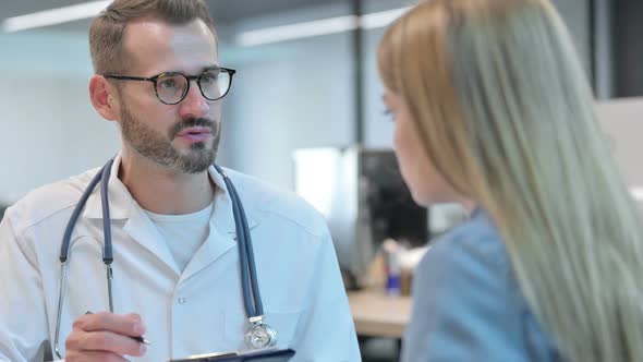 Middle Aged Male Doctor Sharing Report with Happy Female Patient