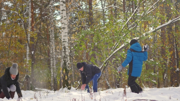 Family Playing By Throwing Snowballs In The Winter Park