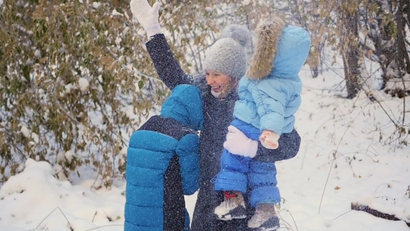 Girl And Child Throwing Snow Over Himself And Enjoys It In The Winter Park