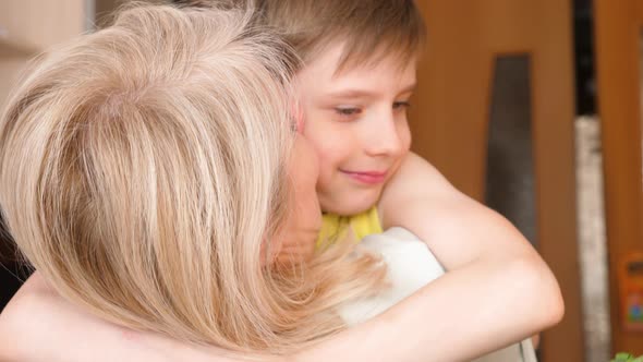 cute caucasian boy 8-9 years old hugging his blonde mom at home.mother's day concept.Child gives flo