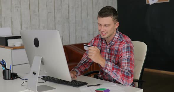 Man Makes Purchases Over the Internet on a Computer and Pays By Credit Card at the Office