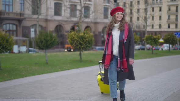 Wide Shot Portrait of Happy Smiling Young Woman Tourist Walking on City Street with Yellow Travel