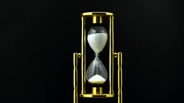 Time Passing While Sand Falls Through Hourglass. Black Background