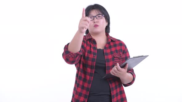 Happy Overweight Asian Hipster Woman Pointing Finger While Holding Clipboard