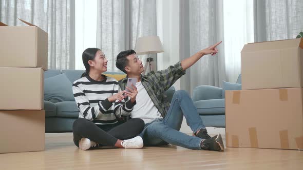 Asian Couple With Cardboard Boxes Smartphone And Discuss About The New House