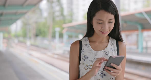 Woman using mobile phone in light rail station