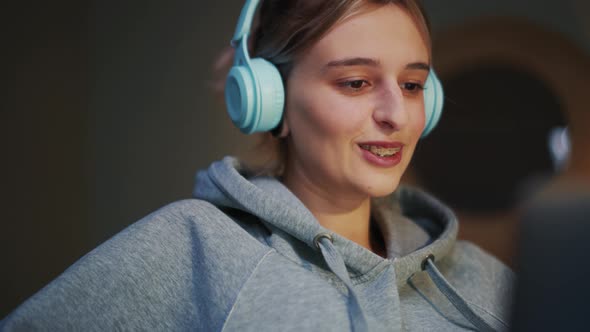 Positive woman in headphones looking at laptop