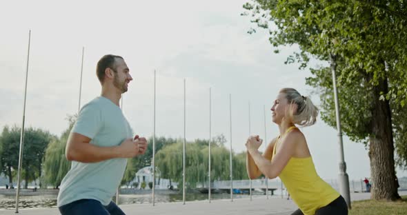 Happy Athletes Squatting on Embankment, Glad Man and Woman in Sportswear Smiling During Fitness