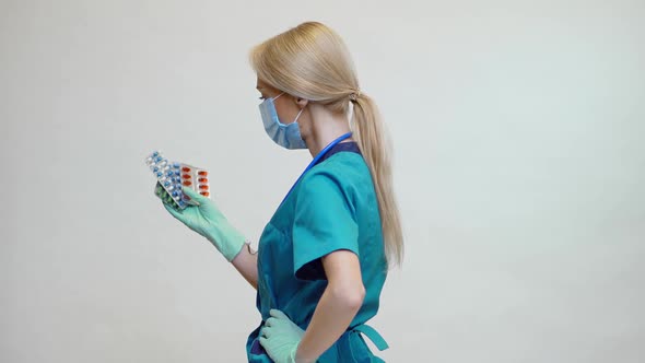 Medical Doctor Nurse Woman Wearing Protective Mask and Rubber or Latex Gloves - Holding Pills