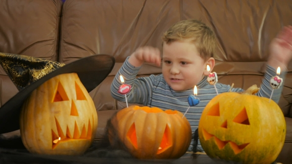 Boy Blowsscary Candles On Pumpkin During Halloween