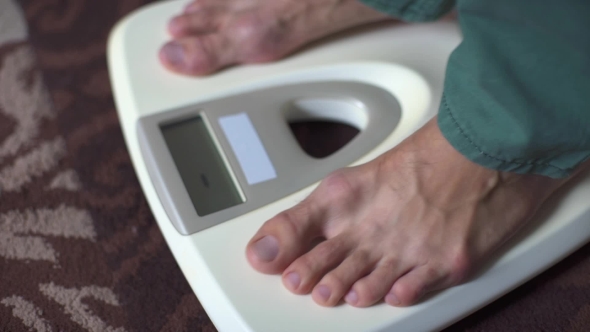 Man Standing On Weight Scales With Bare Foot