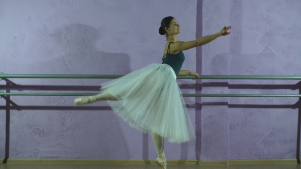 Wearing Pointe Shoes Ballerina Dances Near Barre In Dancing Hall