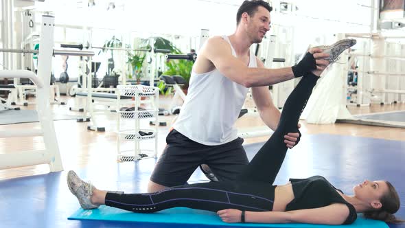 Fitness Trainer Stretching Leg of Young Woman.