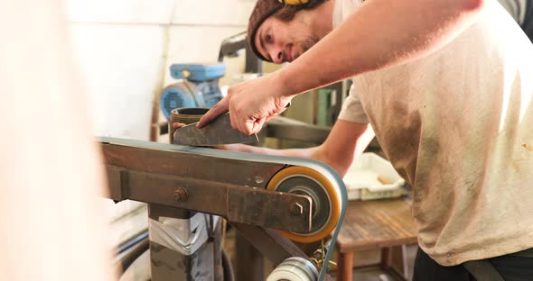 Bladesmith sharpening a blade on belt grinder