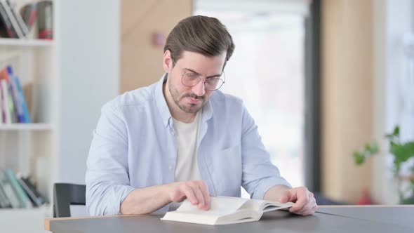 Man in Glasses Reading Book in Office
