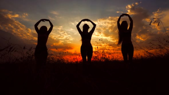 Silhouettes Against Red Sunset of Three Young