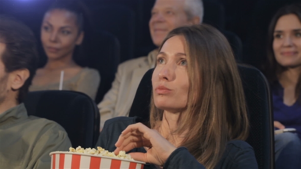 Woman Puts Popcorn Into Her Mouth At The Movie Theater