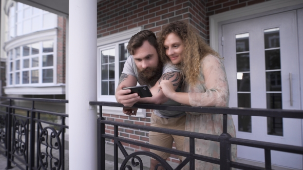 Young Couple Having Bent To a Handrail Near The House