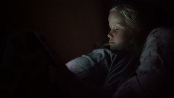 Five Year Old Girl Looking Cartoon Lying On The Couch In The Dark
