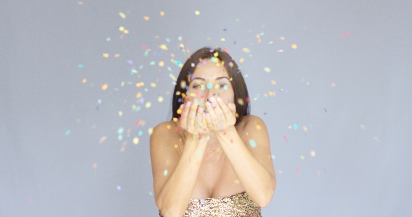 Young Woman Blowing Colorful New Year Confetti