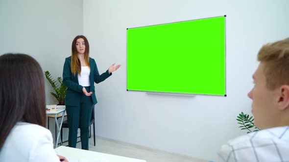 Young Female Teacher Standing near Green Screen Board Giving Lecture for Students