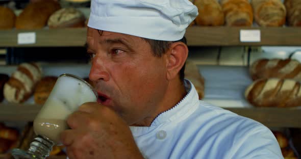 Chef drinking chocolate milkshake in the commercial kitchen 