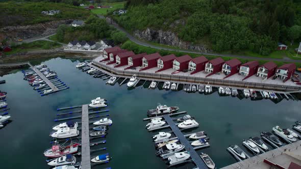 Aerial orbit shot of Tonnes Harbor with Norwegian holiday Cabins close to the sea on a calm day