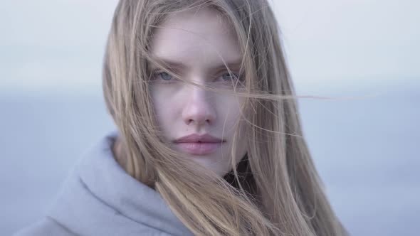 Portrait of Beautiful Young Blond Woman with Long Hair and Blue Eyes Looking in the Camera