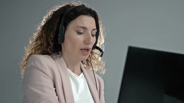 Customer Support Agent or Call Center with Headset Works on Desktop Computer While Supporting the