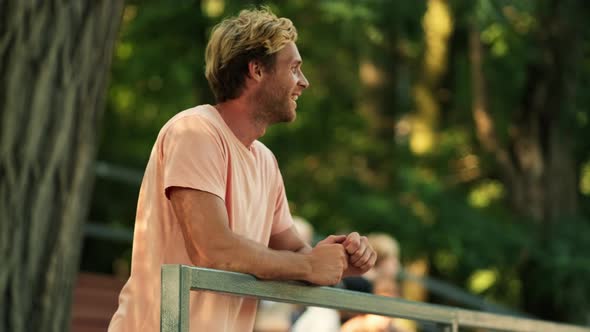 A happy father fan is standing in the stands at the park at summer