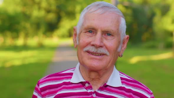 Lovely Cheerful Senior Old Grayhaired Grandfather in Casual Red Tshirt on Summer Park Background