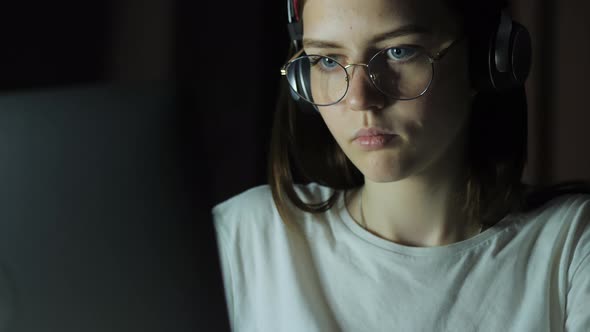 Teenage Girl with Glasses Looks at the Monitor Plays a Game Reads Studies Late at Night