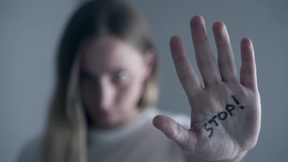 Woman with Bruises on Her Face Showing Stop Sign, Palm in Focus