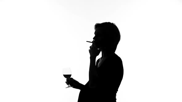 Silhouette of Pregnant Woman Smoking Cigarette and Drinking Glass of Wine