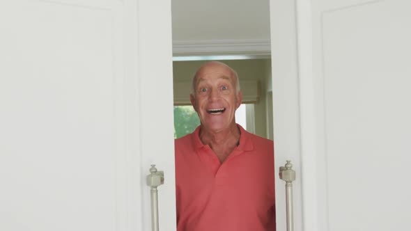 Portrait of smiling senior caucasian man looking at camera and opening door