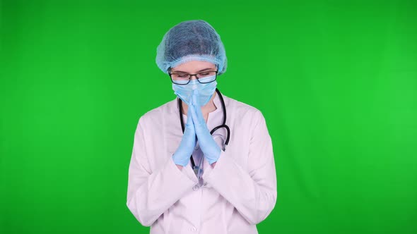 Portrait of Female Praying Doctor in Glasses, Dressed in White Medical Uniform, with Stethoscope, in