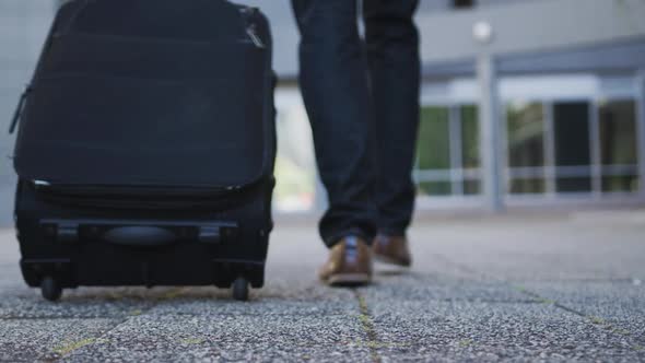 Low section of african american businessman walking with suitcase in street