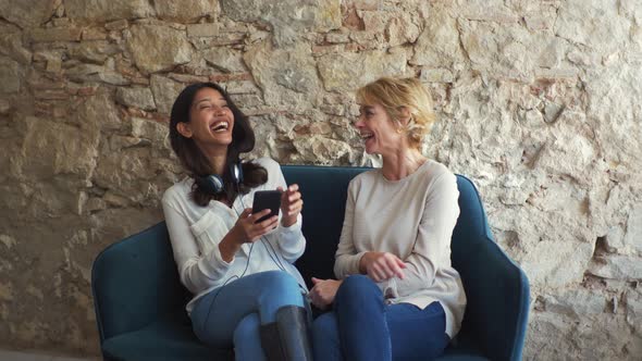 Colleagues using smartphone and sitting on a couch at the office