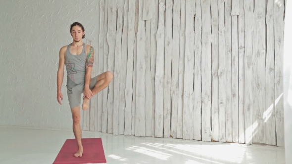 Young Sporty Man Practicing Yoga In Fitness Studio