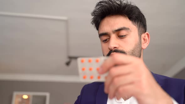 Man examining pill in hand.