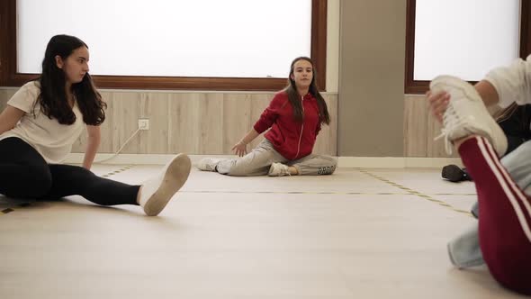 Young women stretching legs before dance class