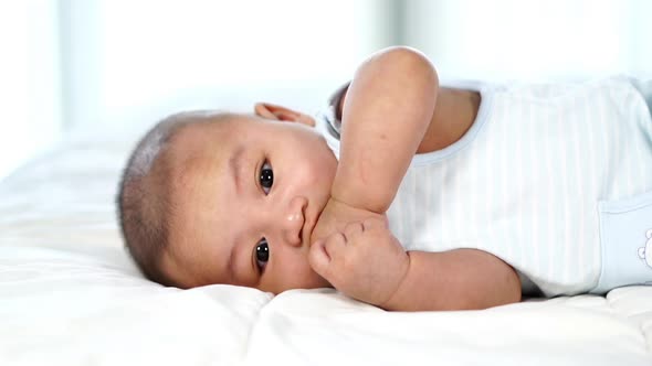 slow-motion of little baby with finger in mouth on a bed