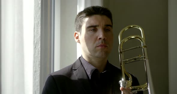 Serious Man in Suit Prepares and Starts Playing Trombone