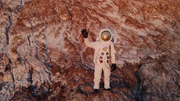 Astronaut Standing on a Rock Waving Hand