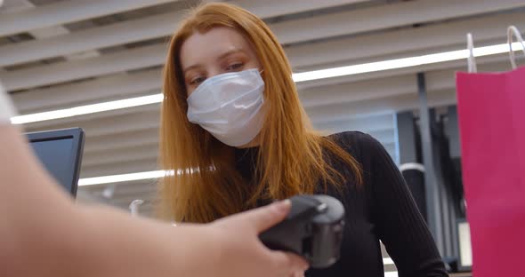 Woman in Retail Shop or Store at Counter Wearing Face Mask and Paying with Credit Card