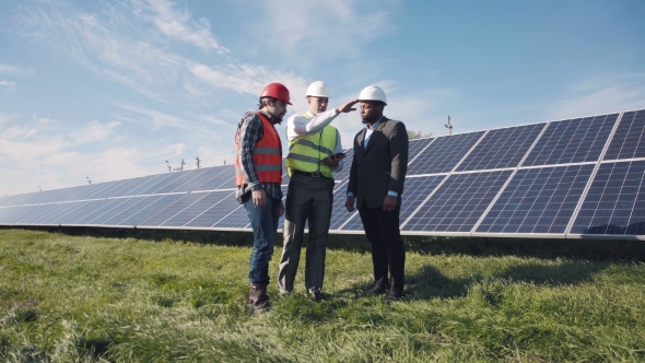 Workers Walking In Beside Row Of Solar Panels