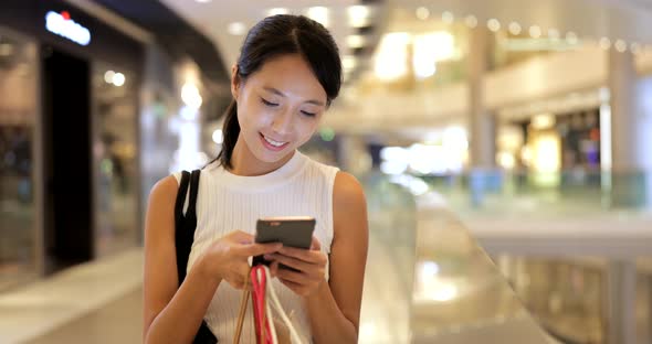 Woman using smart phone with shopping bags 