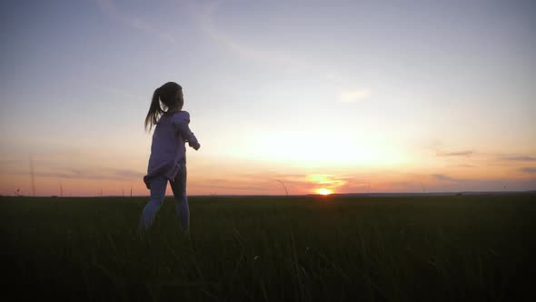 Little Girl Is Running on Meadow at Sunset Time. The Concept of Childhood Dreams or the Desire